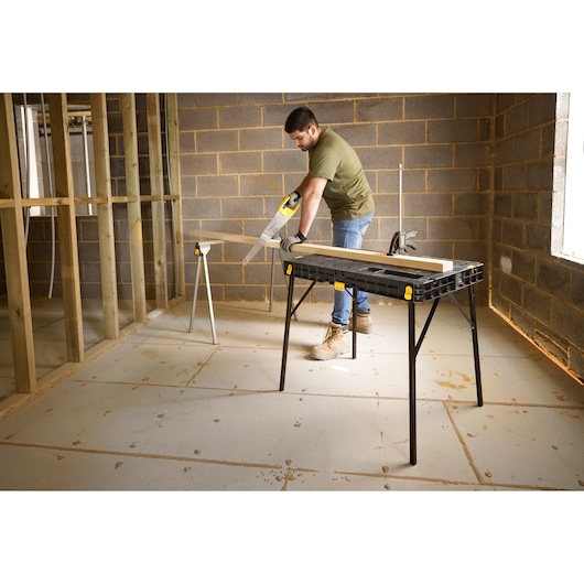 STANLEY STST83492-1 workbench table, black plastic top with yellow accents, used in construction site.