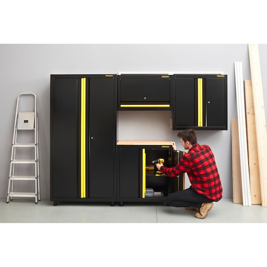 STANLEY STST97599-1 storage cabinets and workbench with yellow accents in a workshop, front angle.